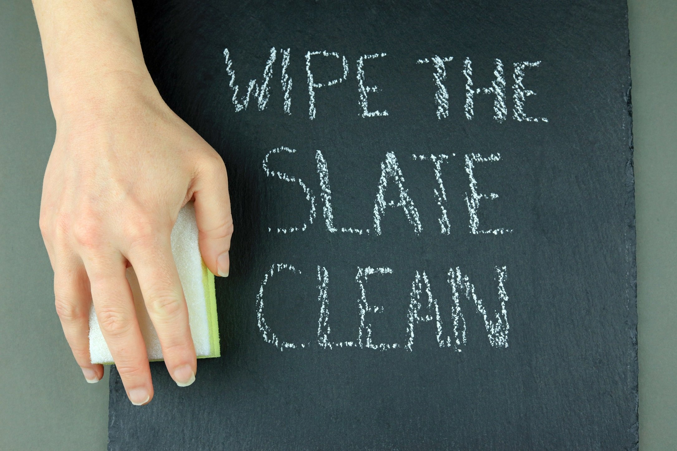 Hand holding sponge on a slate with the words 