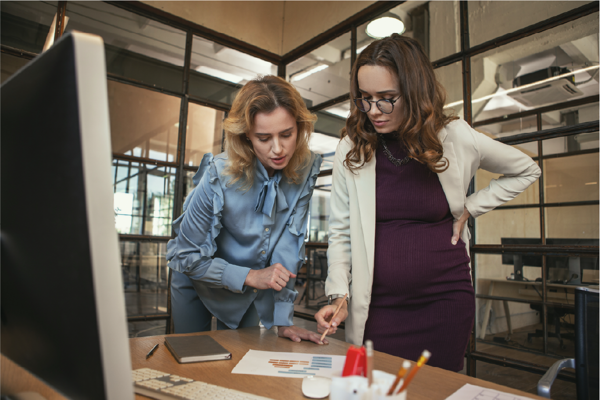 An HR manager and an employee, both women, reading a document on a table in the office.